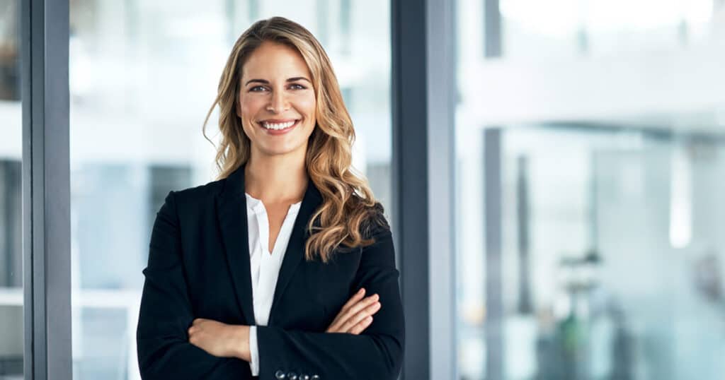 confident female executive standing with arms crossed in modern office